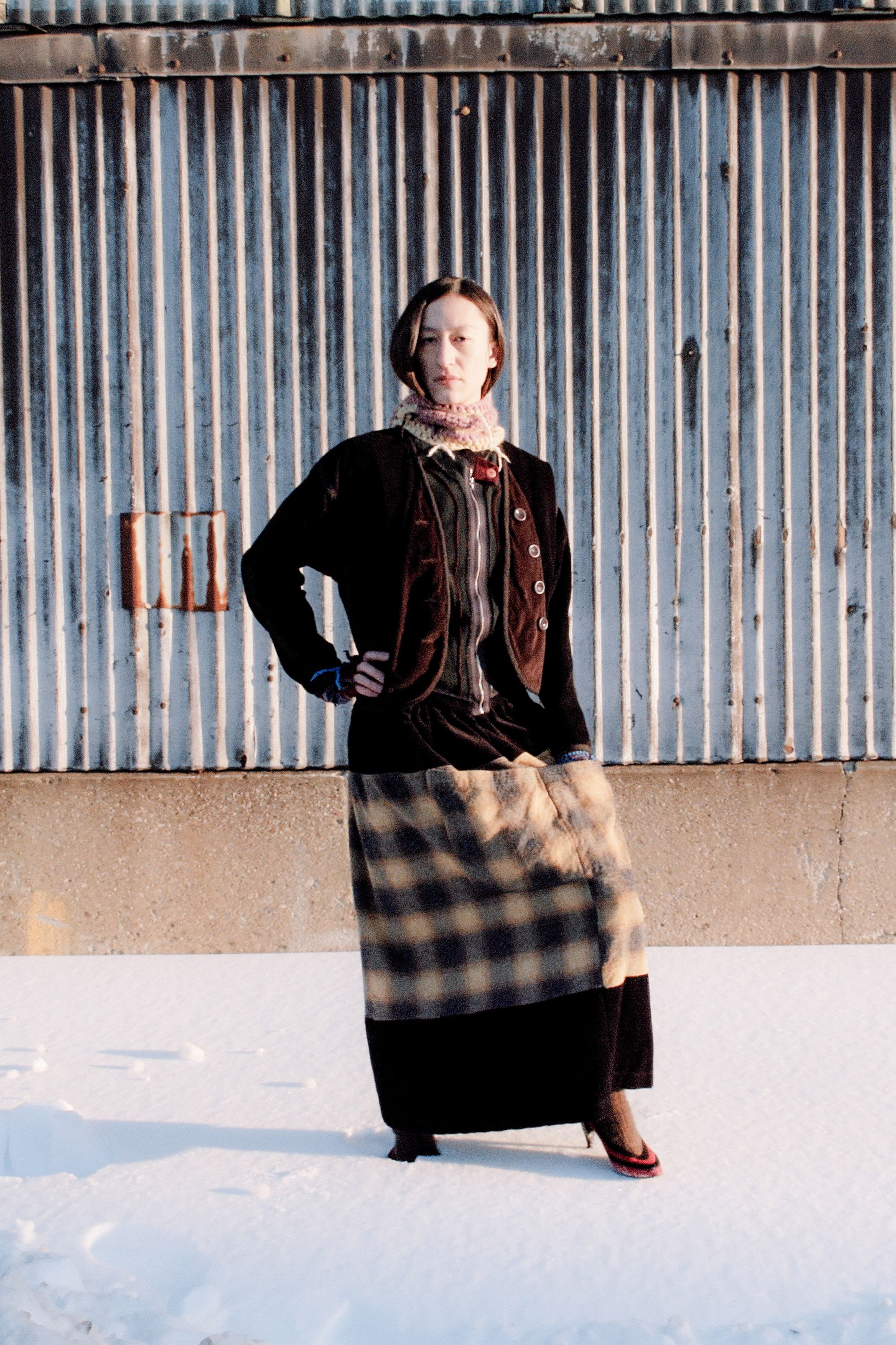 SC103以粗线针织与格纹拼接演绎实验性层叠，工业背景下的鲜明色块与流苏细节释放先锋张力，呈现出手工质感与未来街头交融的视觉冲击-顽石频道趋势研究
